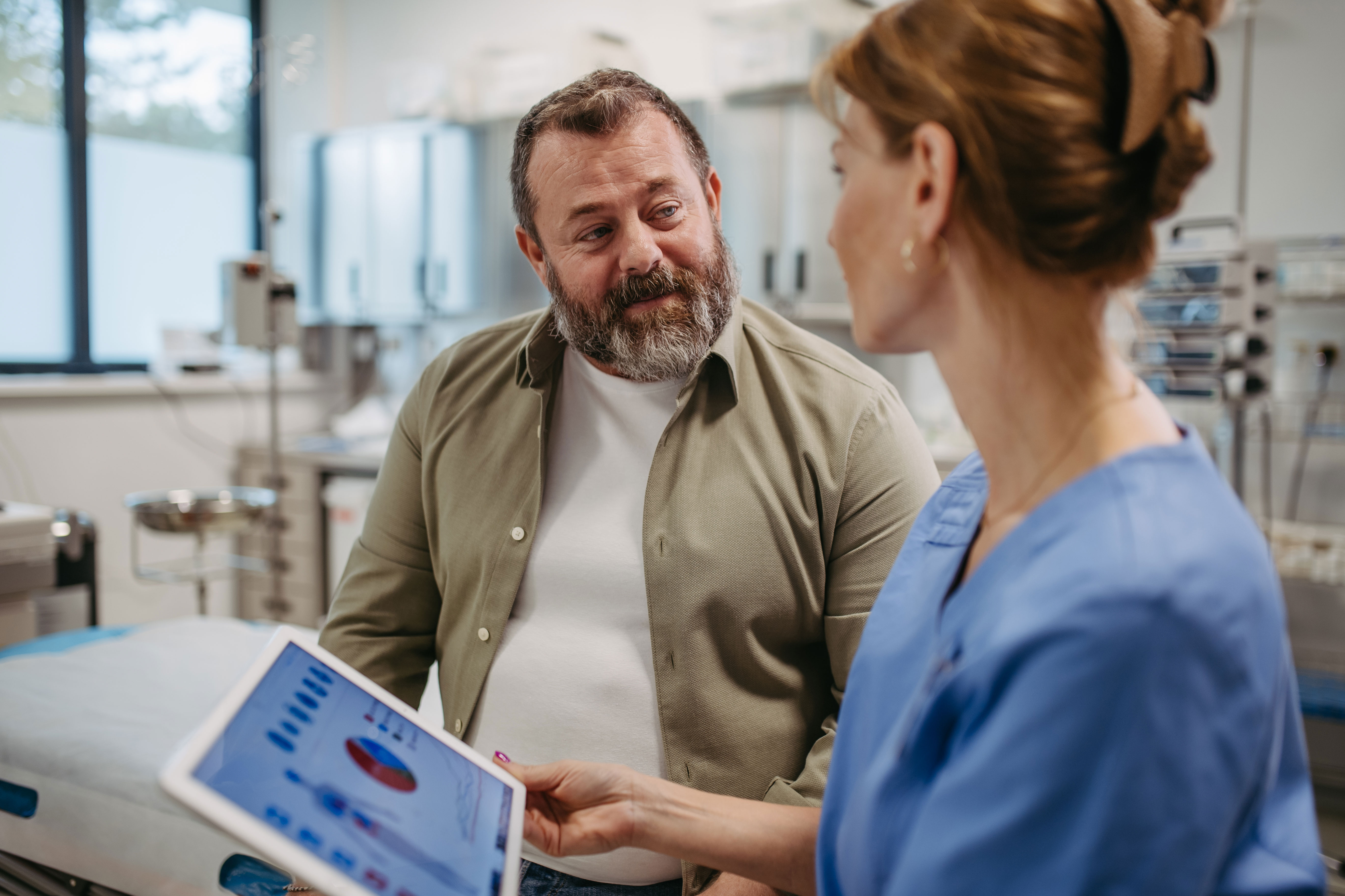Man talks with healthcare employee about medical stats Man talks with healthcare employee about medical stats