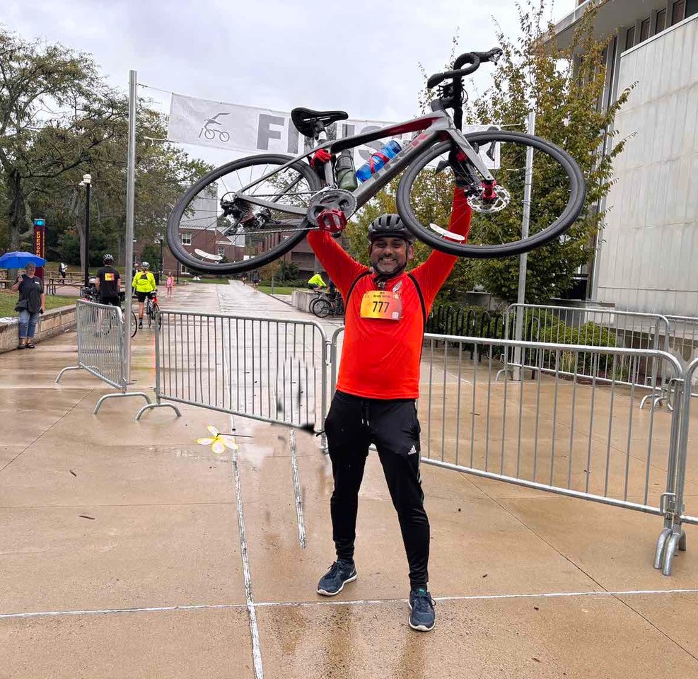 Person holding up bike at finish of biking event