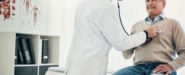Doctor using stethoscope to listen to older man's heart