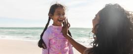 Mom putting sunscreen on daughter at the beach