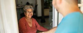 Nurse greets older woman at her door