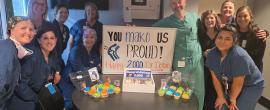A group celebrates Dr. William Doran with a sign that says "You Mako Us Proud!"