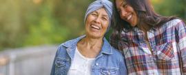Mother with cancer and daughter smile while walking on a trail