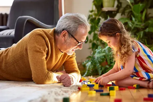 Grandfather playing blocks with his granddaughter