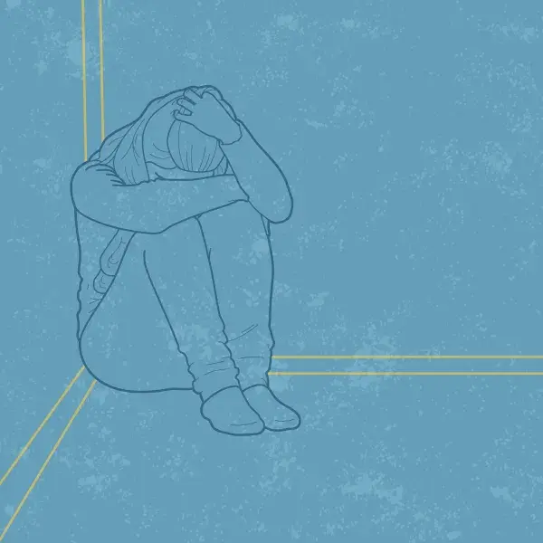 A person sitting on the ground with their head on their knees