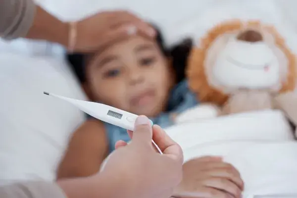 A caregiver monitoring temperature of a child with flu symptoms