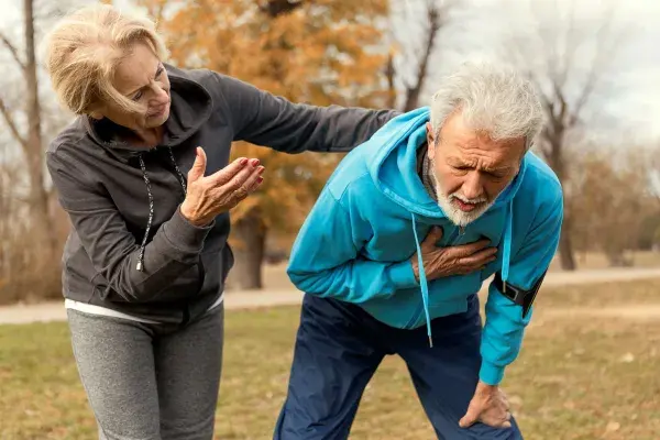 Man in exercise clothes clutching his chest with concerned woman looking on