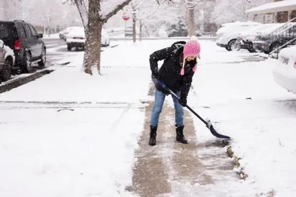 Woman shoveling snow off the sidewalk