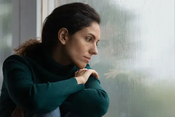 Woman staring into rainy window