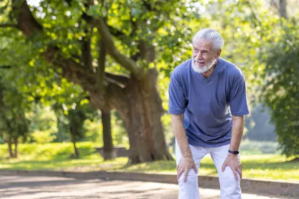 Senior man in the park with hands on legs