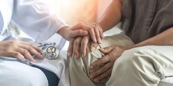 Healthcare provider with hand on top of patient's hand