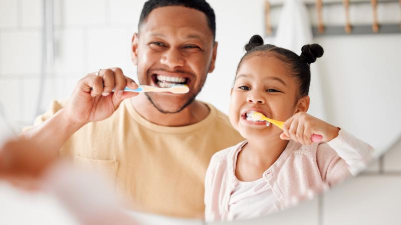 Father and daughter brushing their teeth