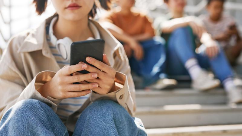 Girl on her phone sitting away from friends