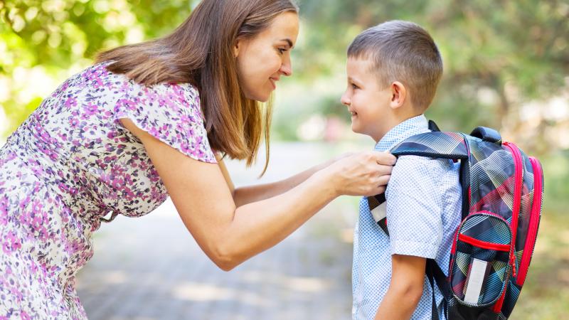 Mother helping son with his backpack