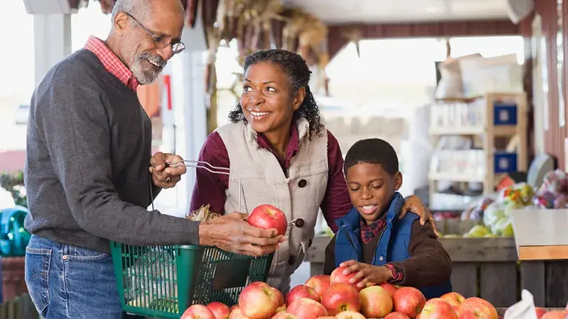 Grandparents and grandchild picking apples at a fall market