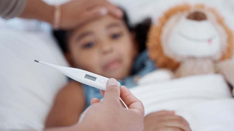 A caregiver monitoring temperature of a child with flu symptoms