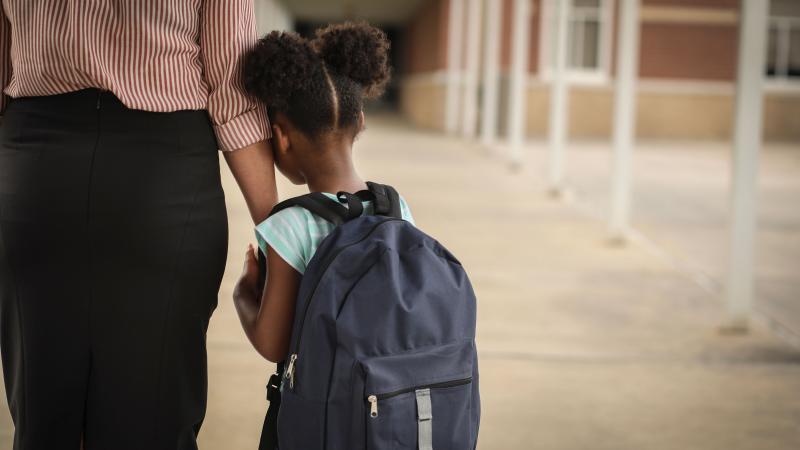 Little girl getting dropped off by mom at school