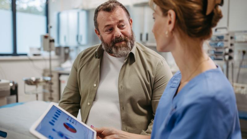 Man talks with healthcare employee about medical stats