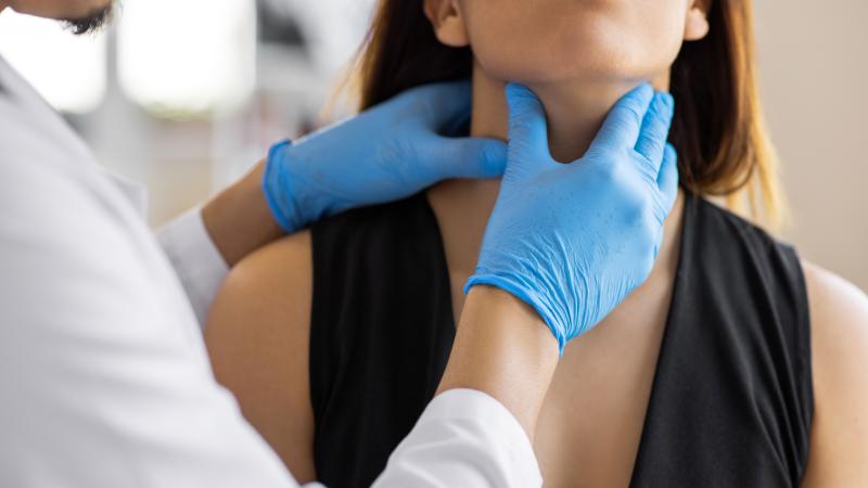 Healthcare provider checks woman's thyroid
