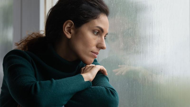 Woman staring into rainy window