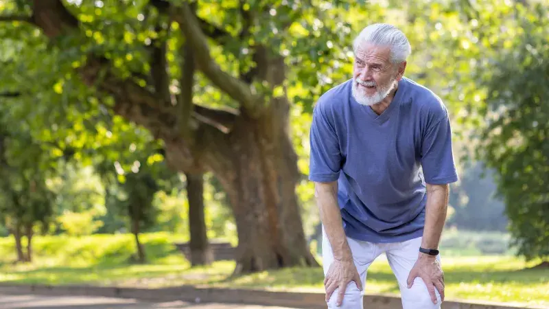 Senior man in the park with hands on legs