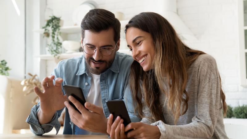 Man and woman on phones smiling