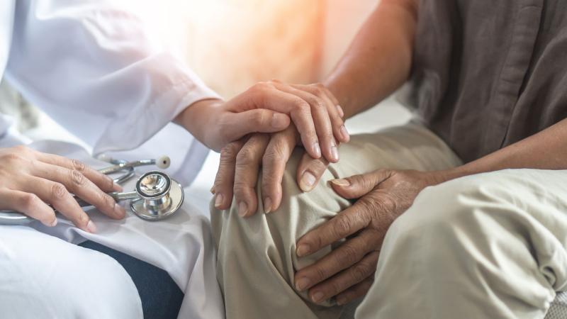 Healthcare provider with hand on top of patient's hand