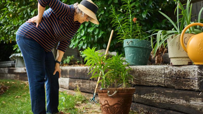 Woman holding her back in pain while gardening
