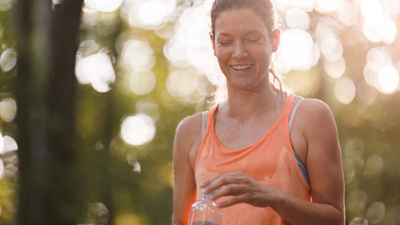 Sweaty female runner taking cap off water bottle