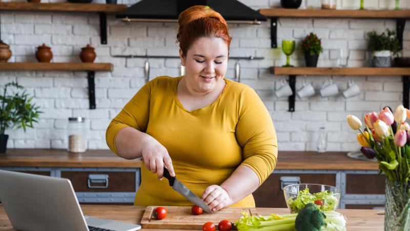 Woman cuts up vegetables for salad
