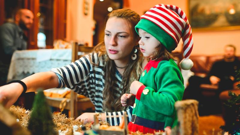 A mother showing her toddler, wearing an elf costume, something