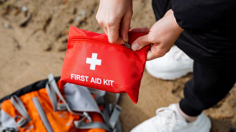 Person about to open a first aid kit on sand