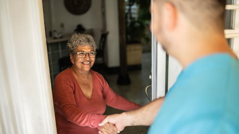 Nurse greets older woman at her door