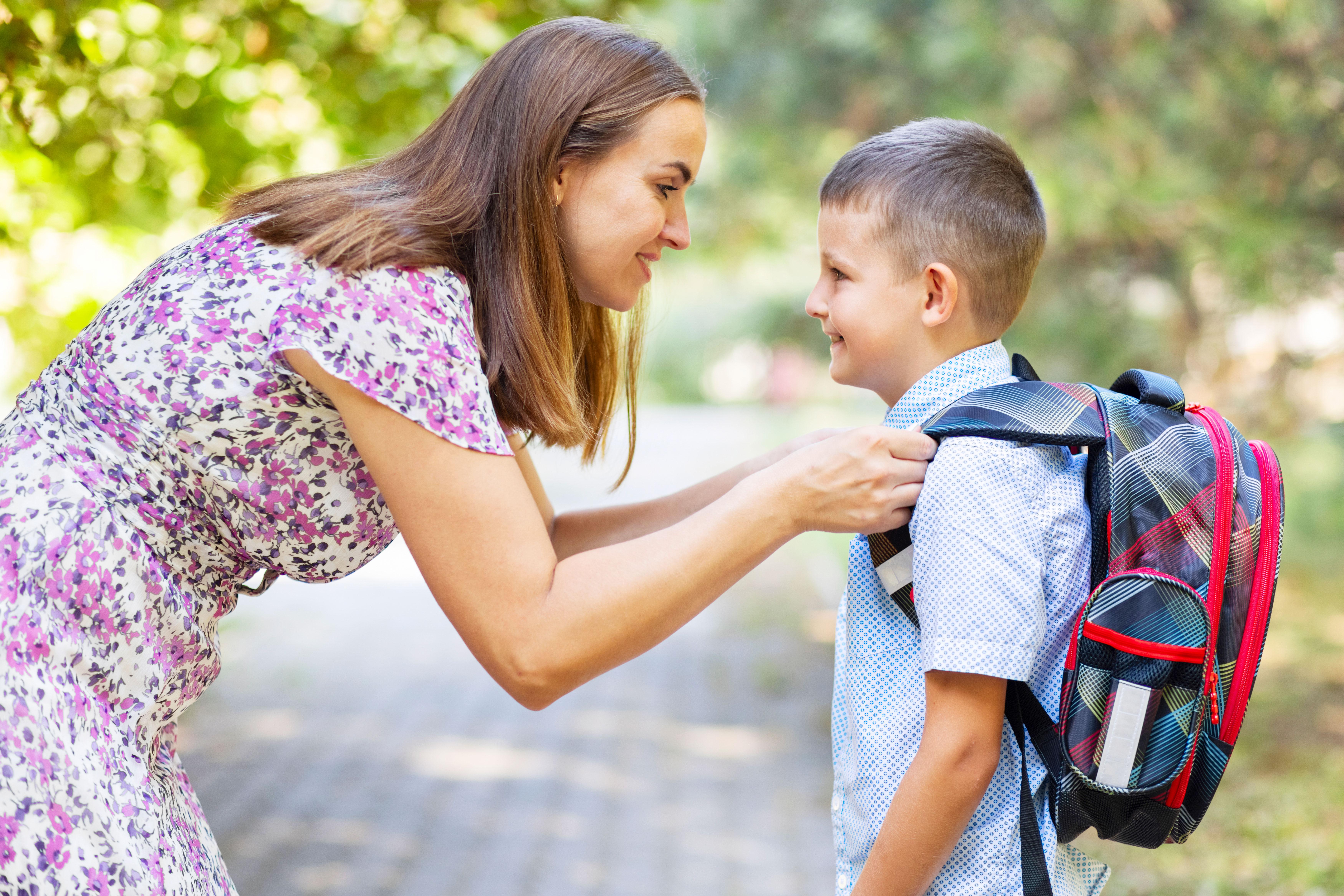 Mother helping son with his backpack