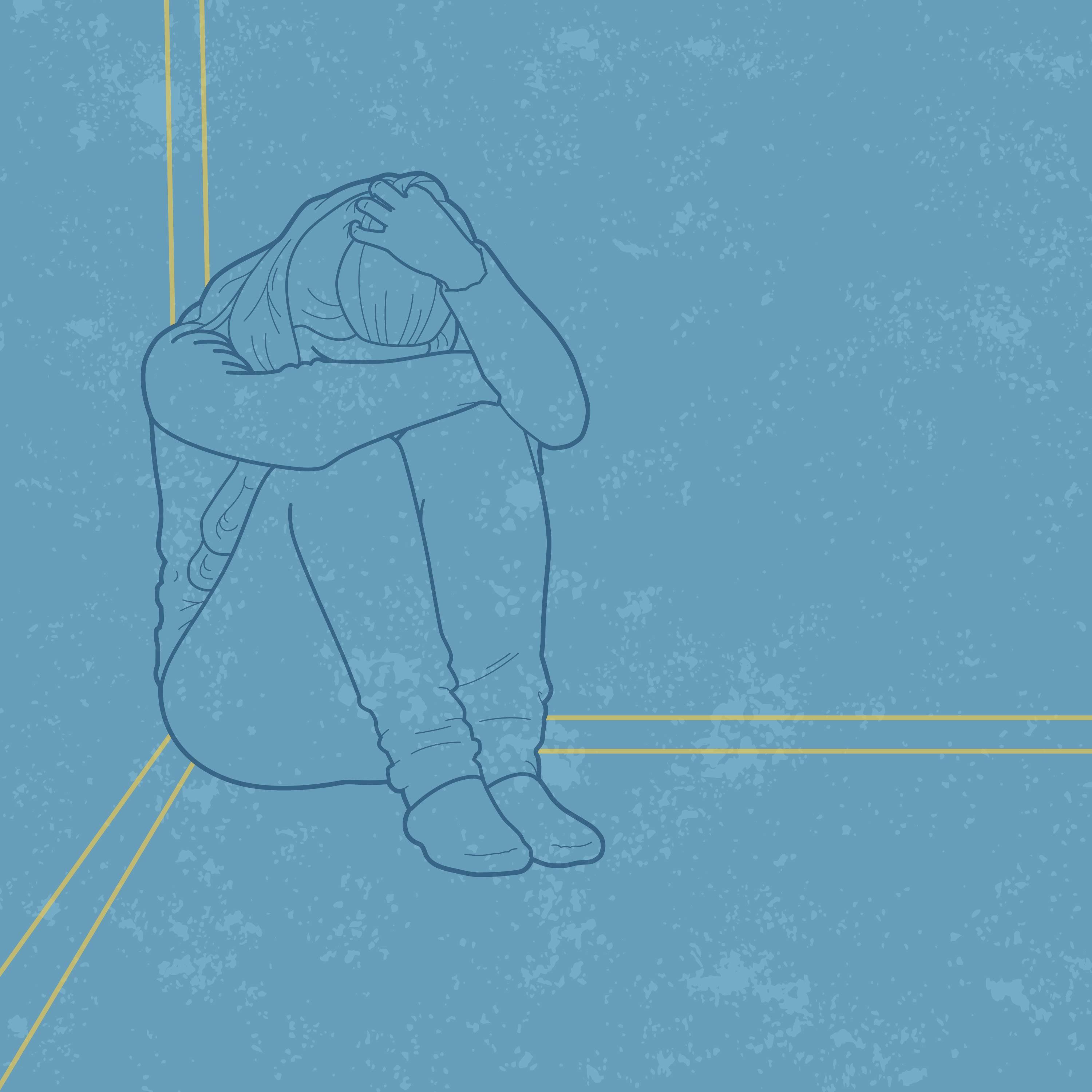 A person sitting on the ground with their head on their knees