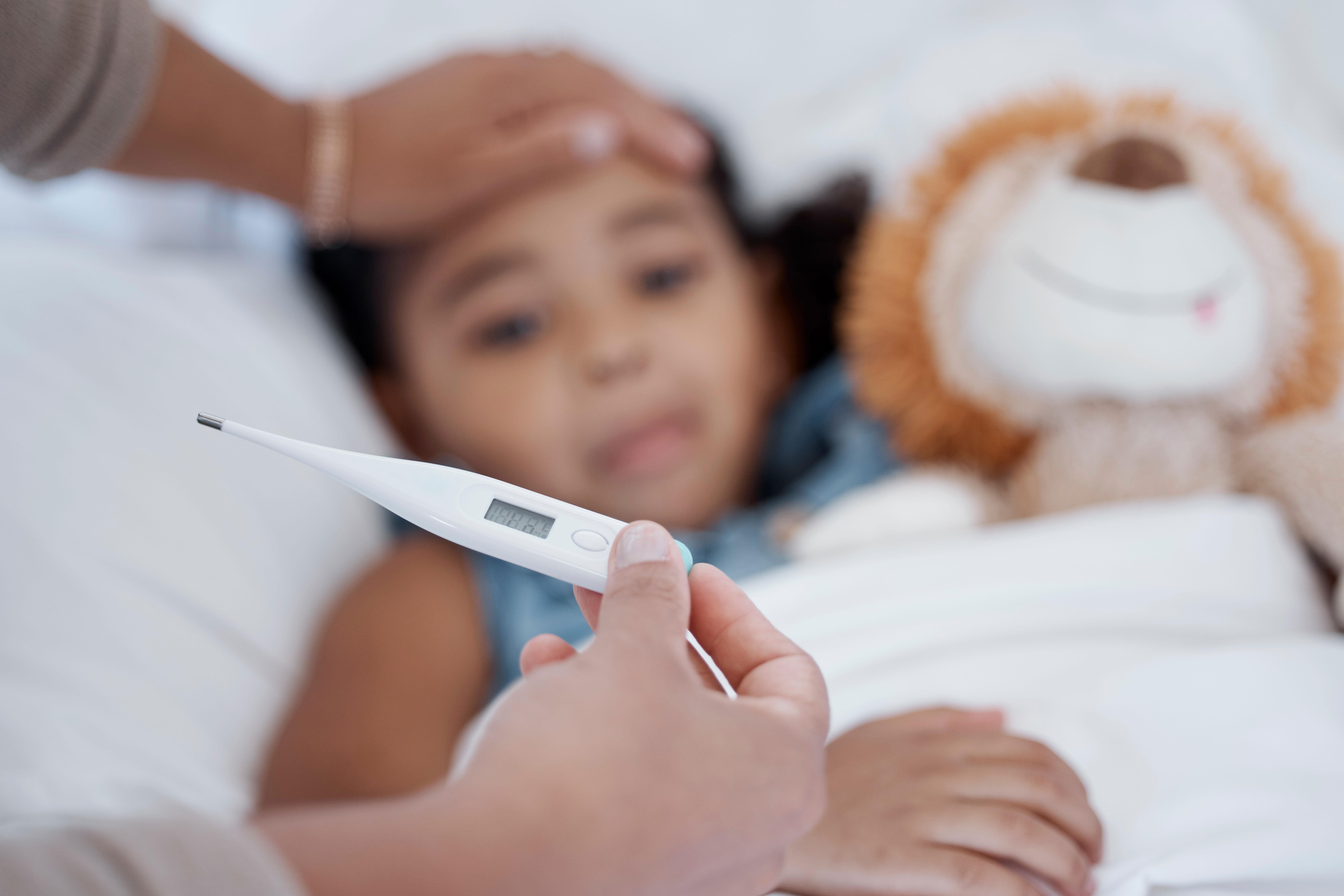 A caregiver monitoring temperature of a child with flu symptoms