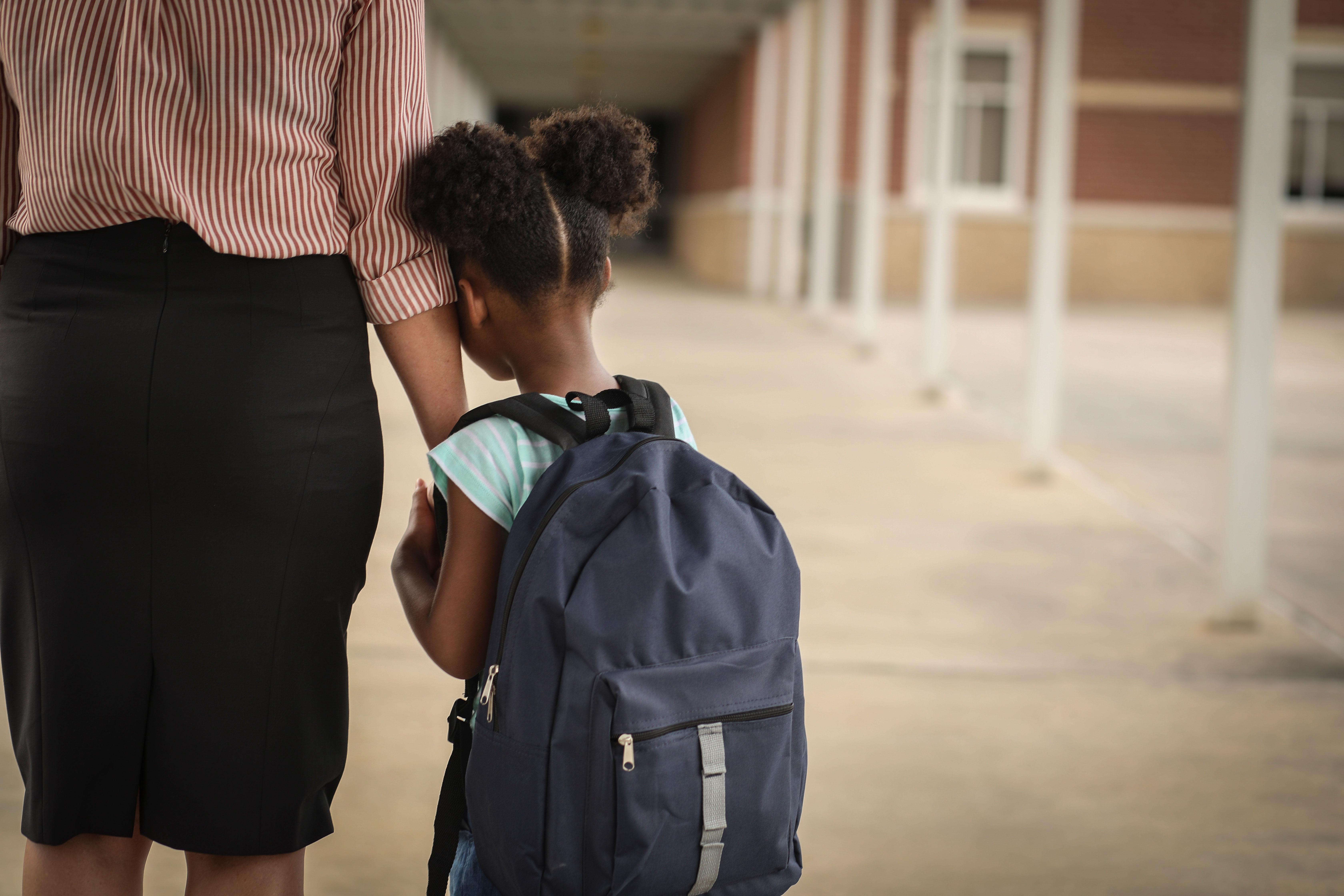 Little girl getting dropped off by mom at school