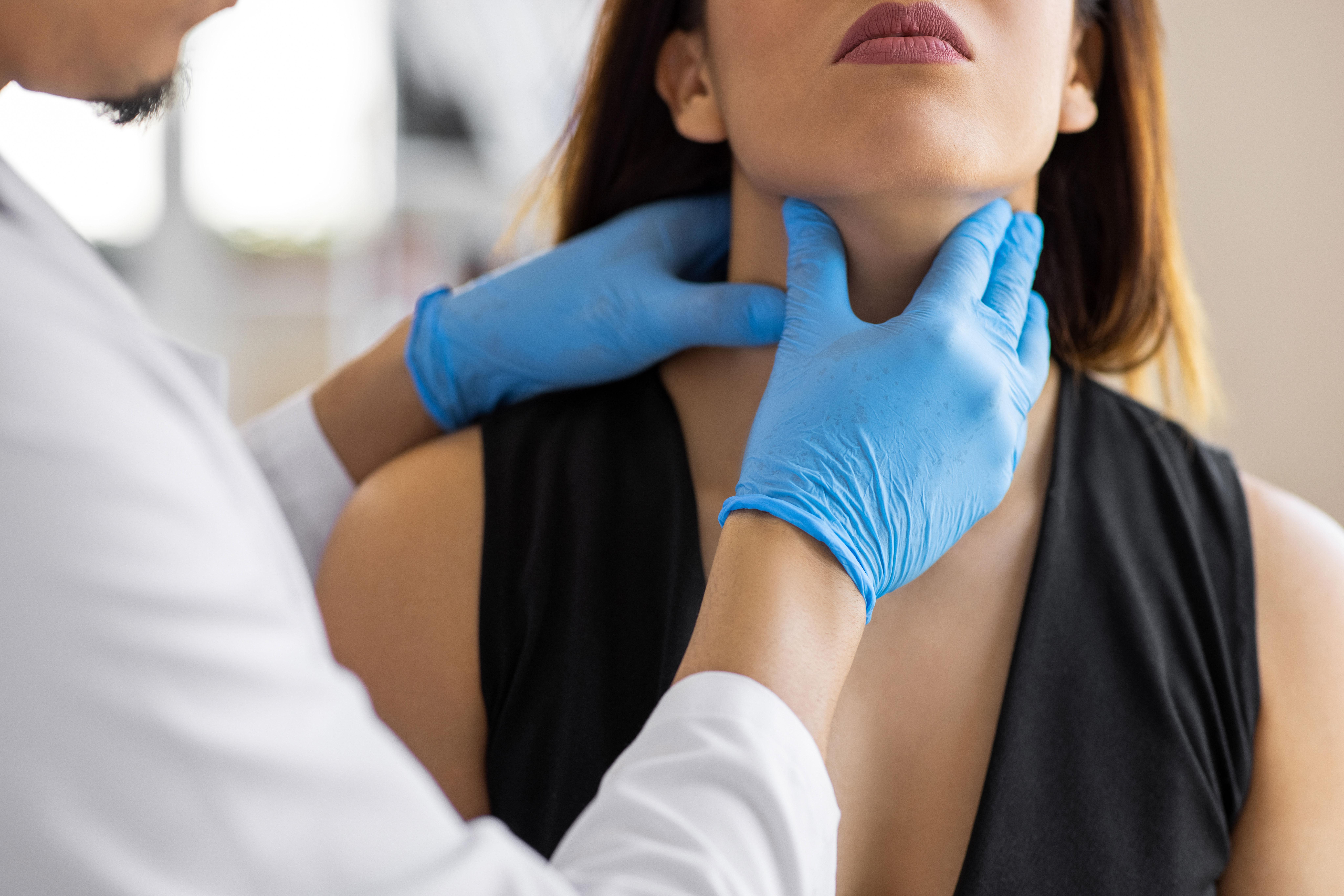 Healthcare provider checks woman's thyroid