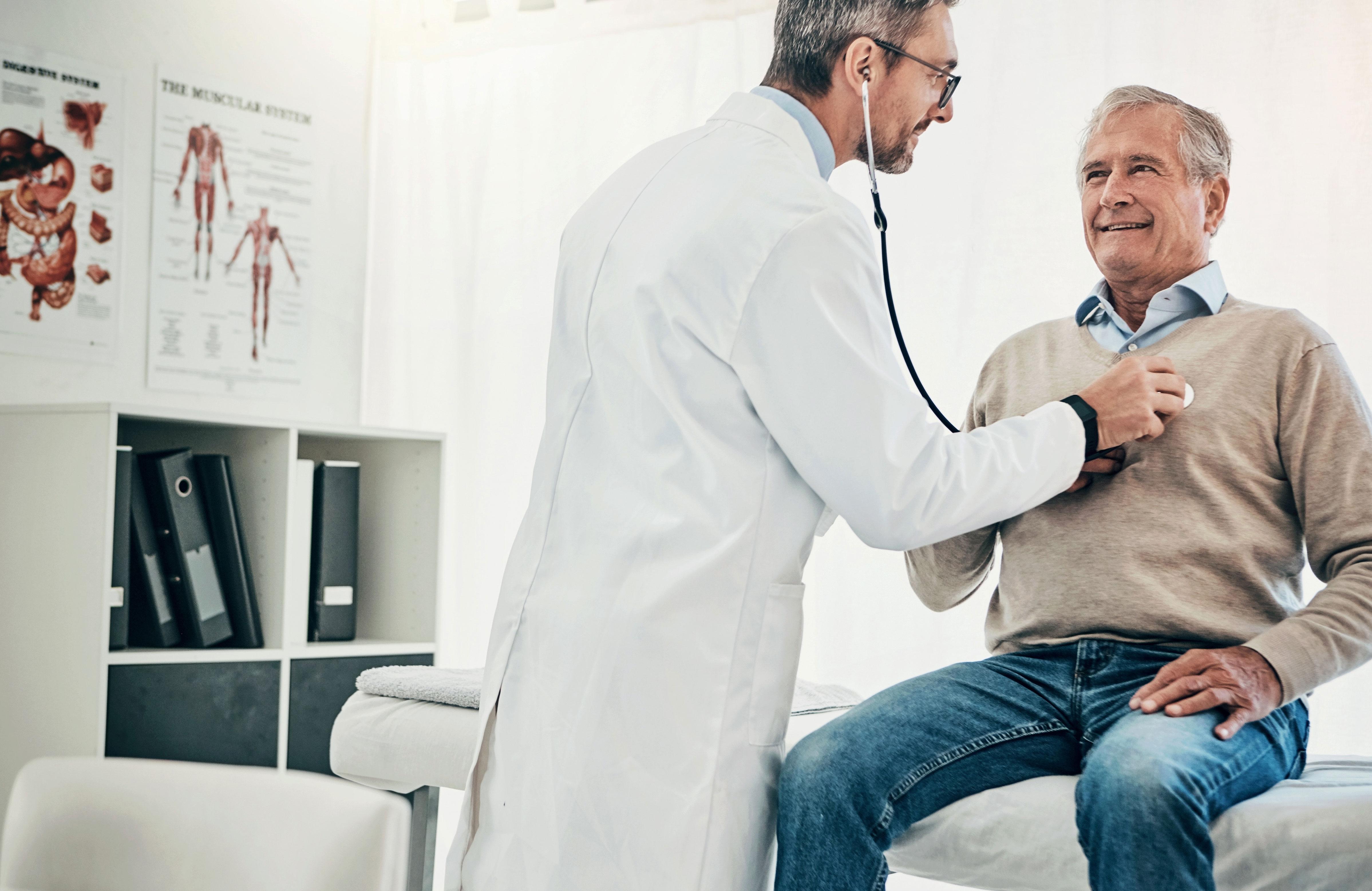 Doctor using stethoscope to listen to older man's heart