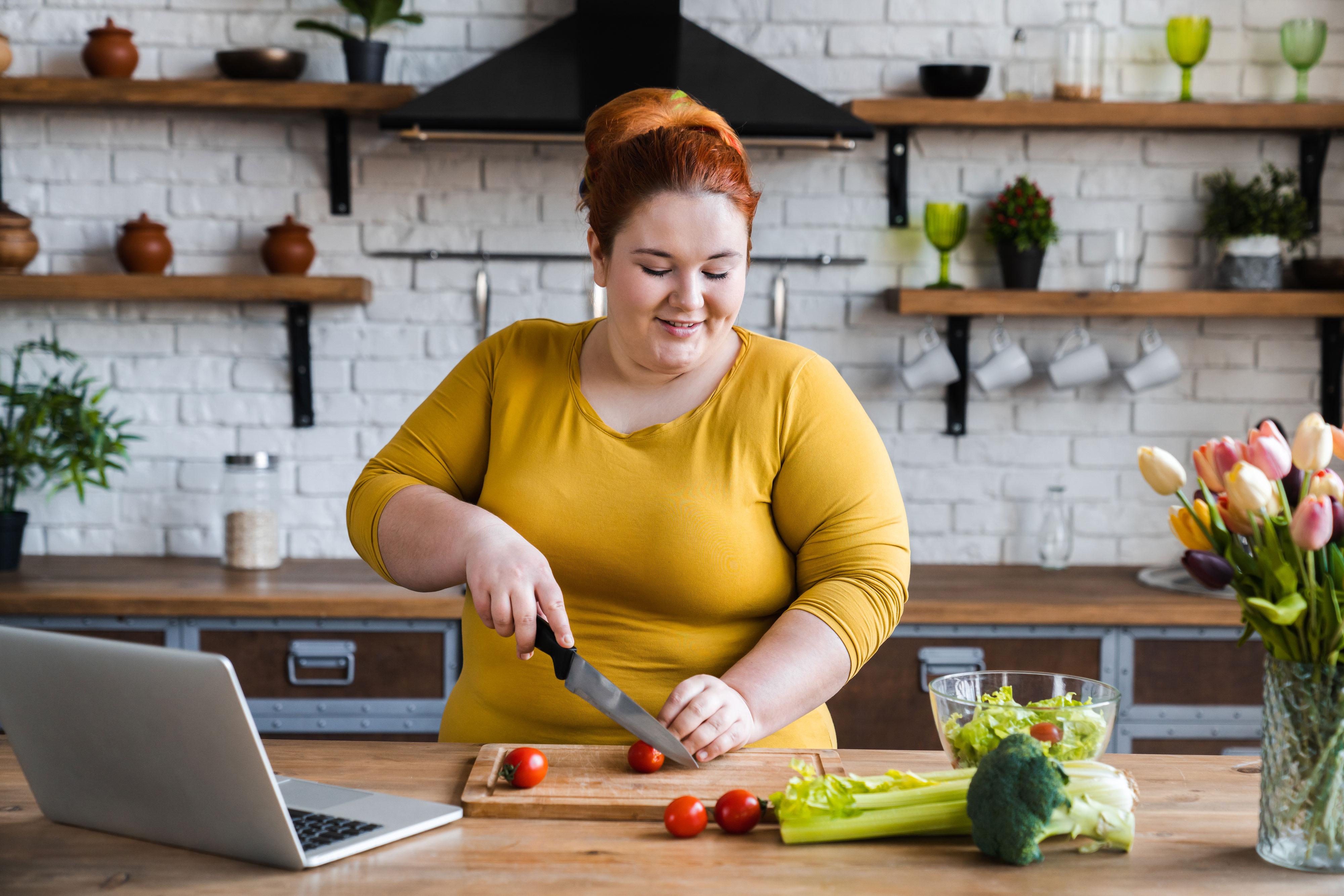 Woman cuts up vegetables for salad