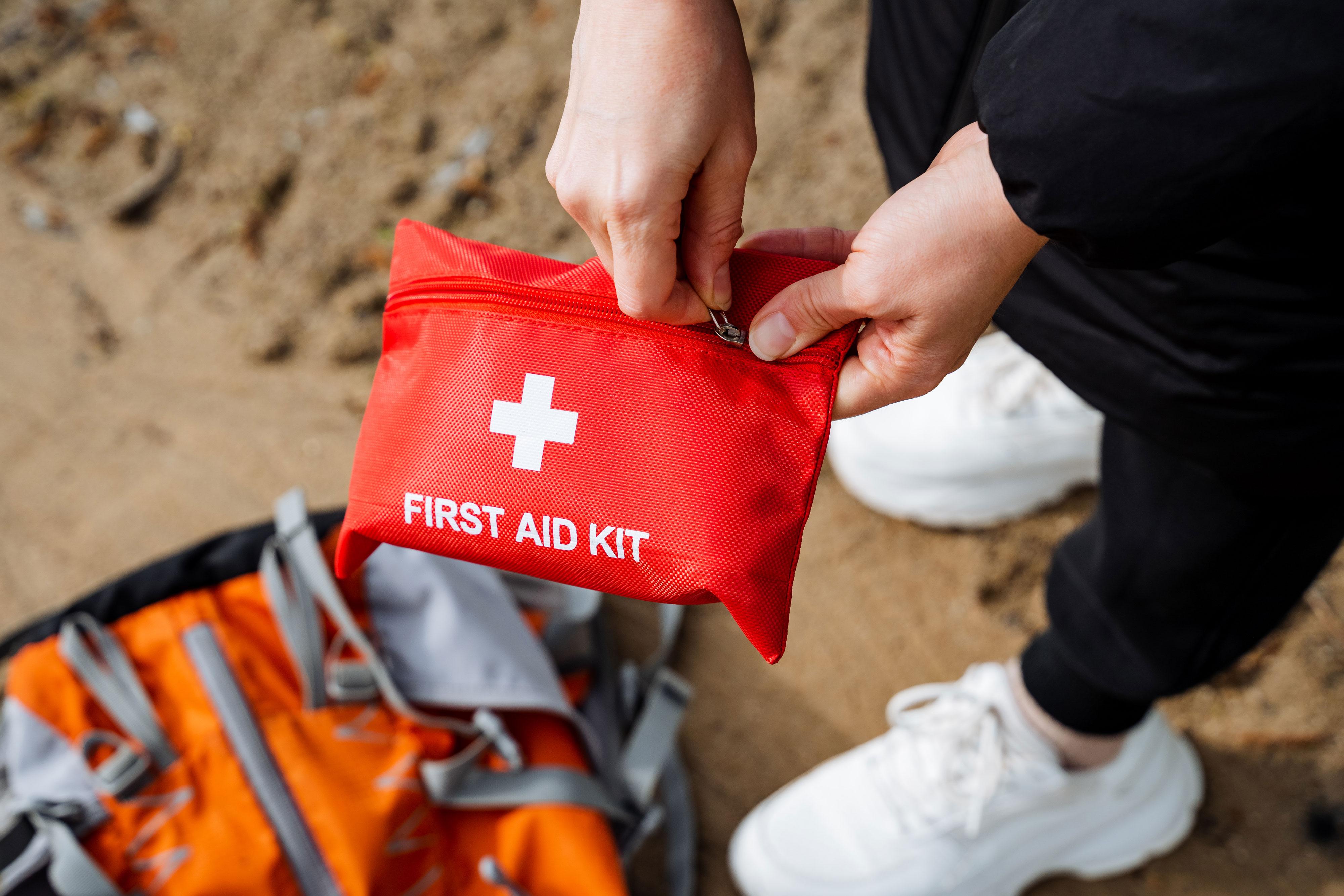 Person about to open a first aid kit on sand