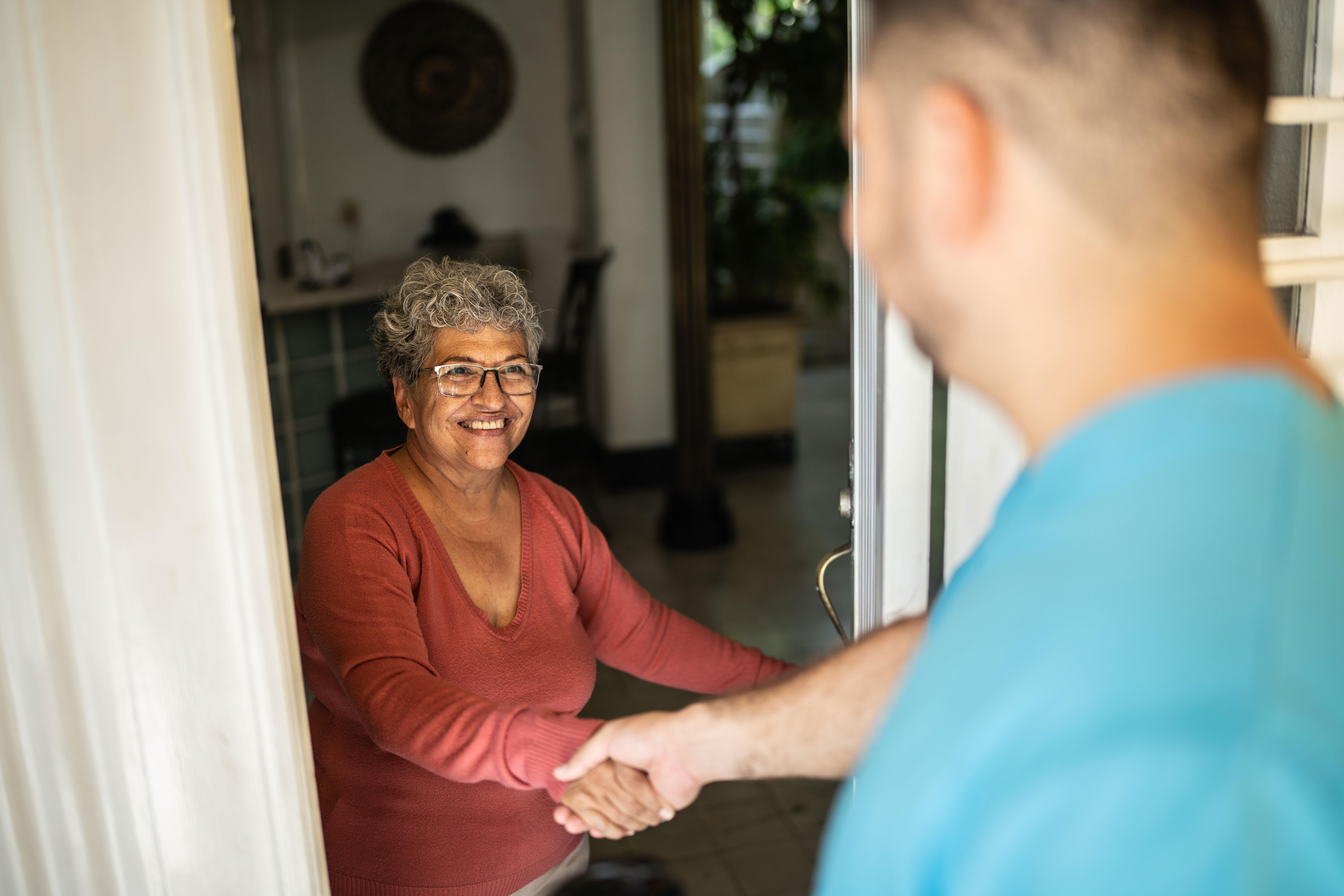 Nurse greets older woman at her door