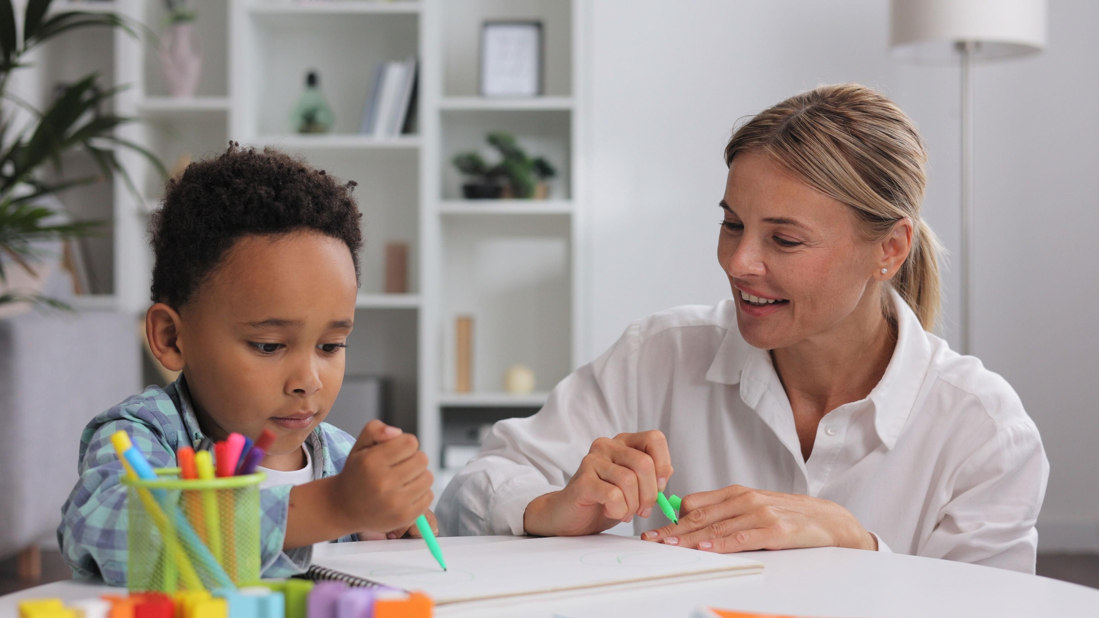 A child works with a teacher on writing