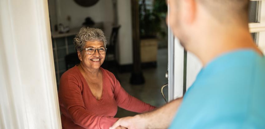 Nurse greets older woman at her door