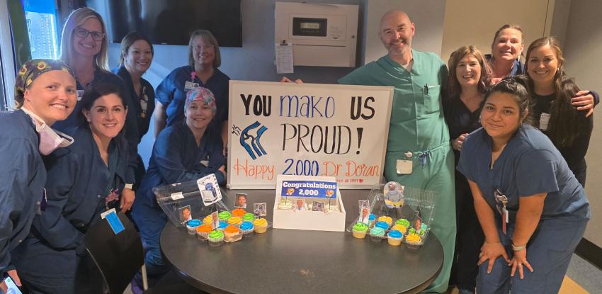 A group celebrates Dr. William Doran with a sign that says "You Mako Us Proud!"