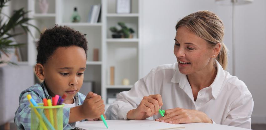 A child works with a teacher on writing