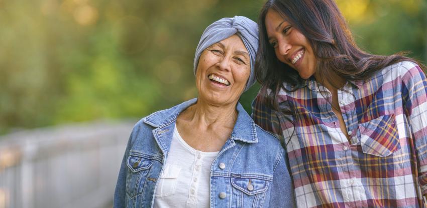 Mother with cancer and daughter smile while walking on a trail