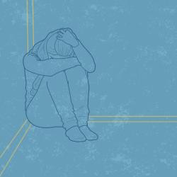 A person sitting on the ground with their head on their knees